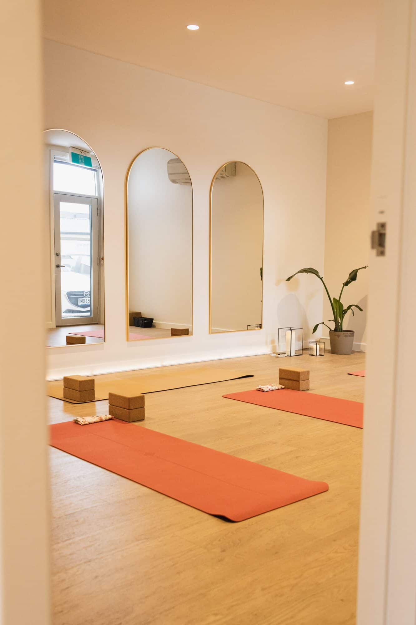 Yoga mats and cork blocks laid out in front of gold arched mirrors in the AM Mind Your Body studio