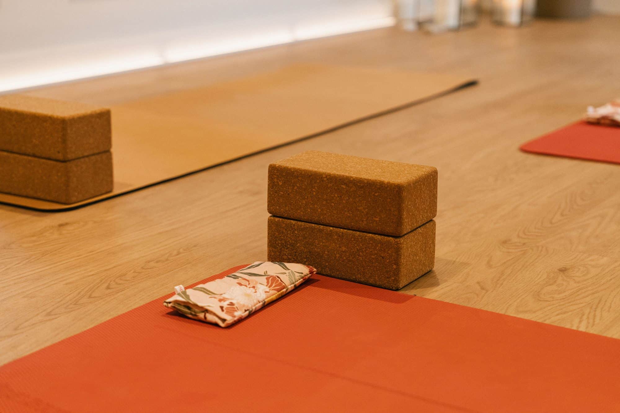 Cork yoga blocks and a lavender eye pillow on a terracotta yoga mat in the studio